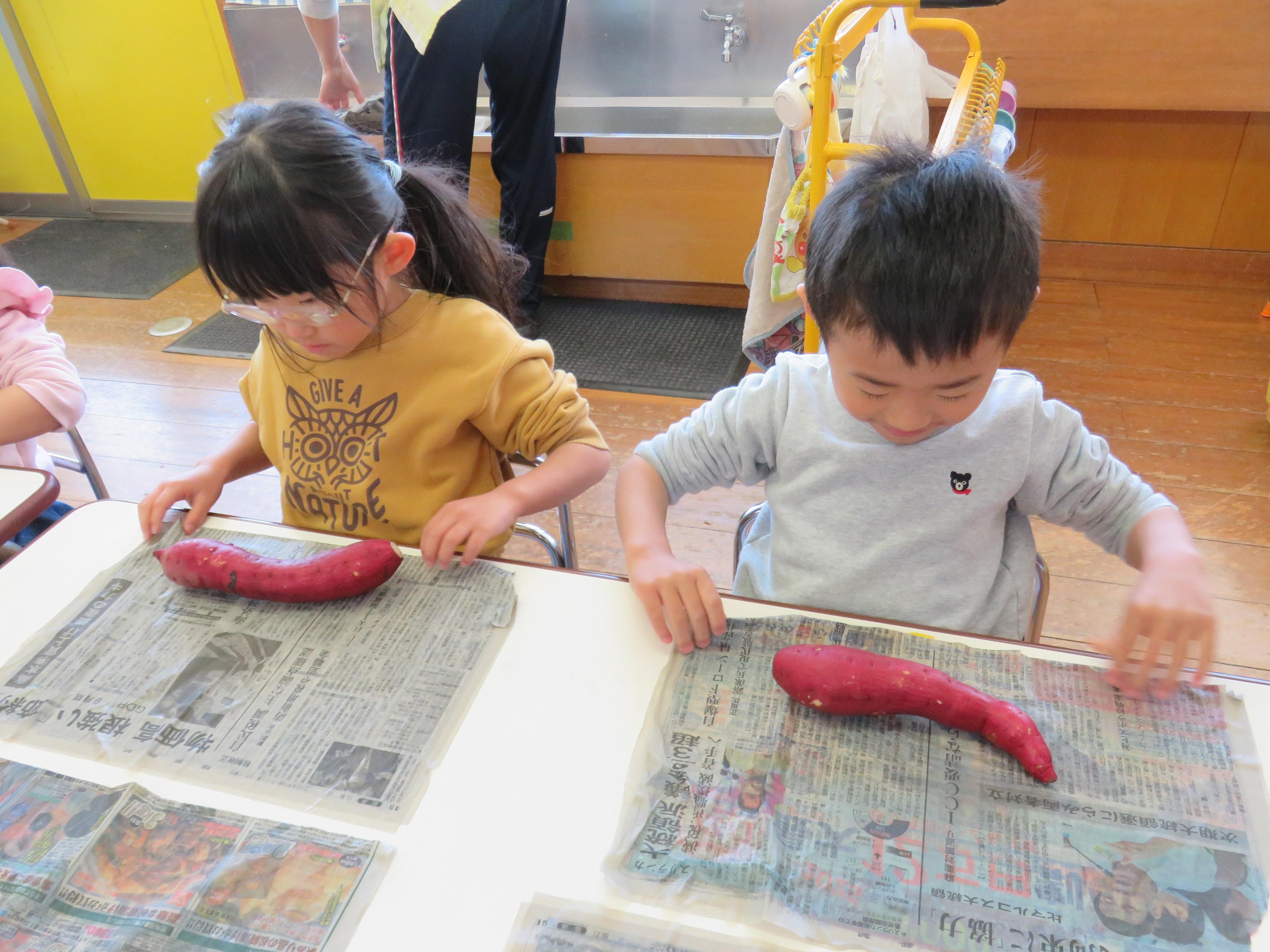 子ども達が洗ったさつまいもを新聞紙に包んでいる写真