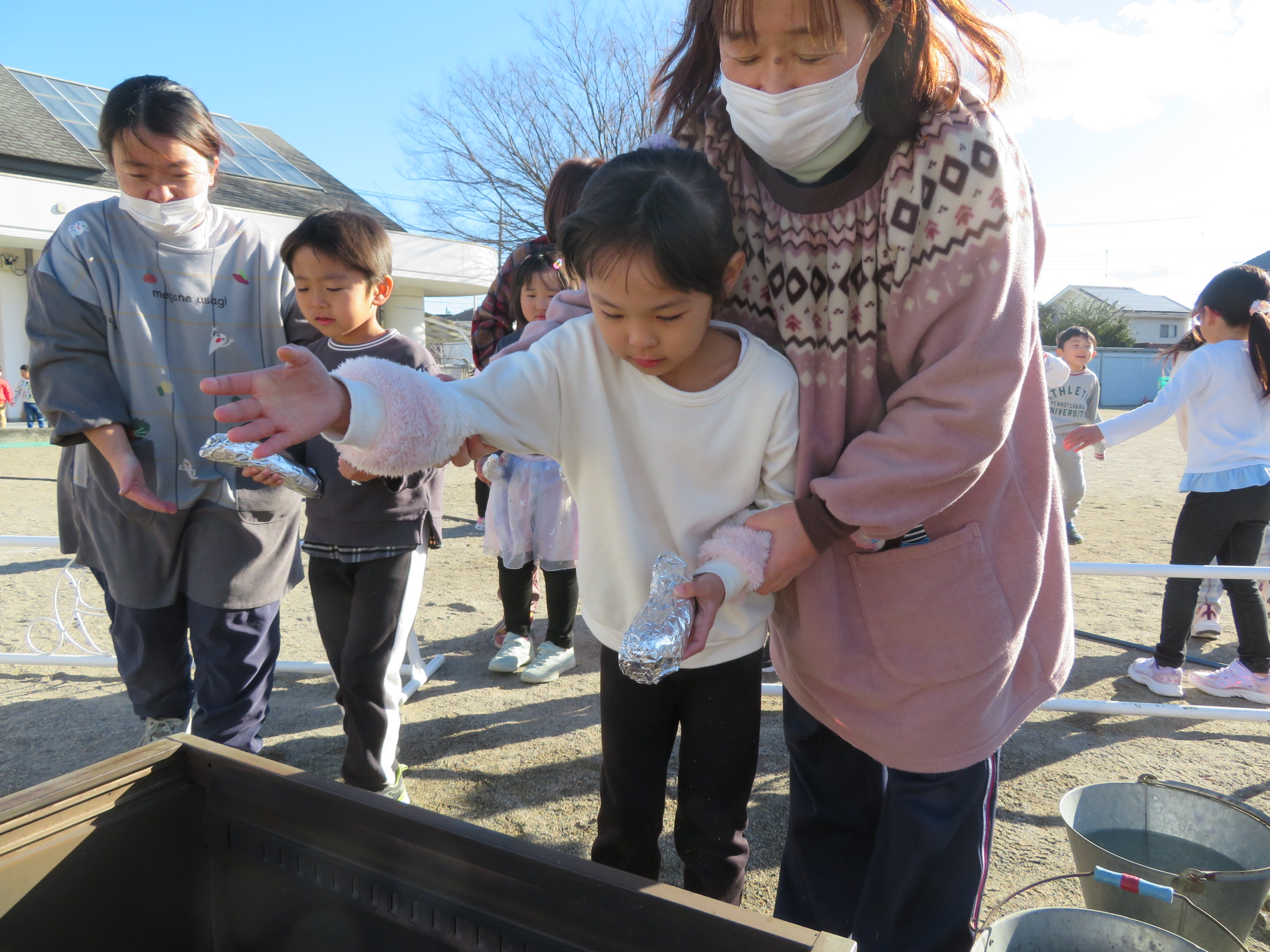 さつまいもを焼きいも器に入れる写真